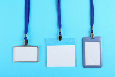 Photo of Blank badges on light blue background, flat lay. Mockup for design