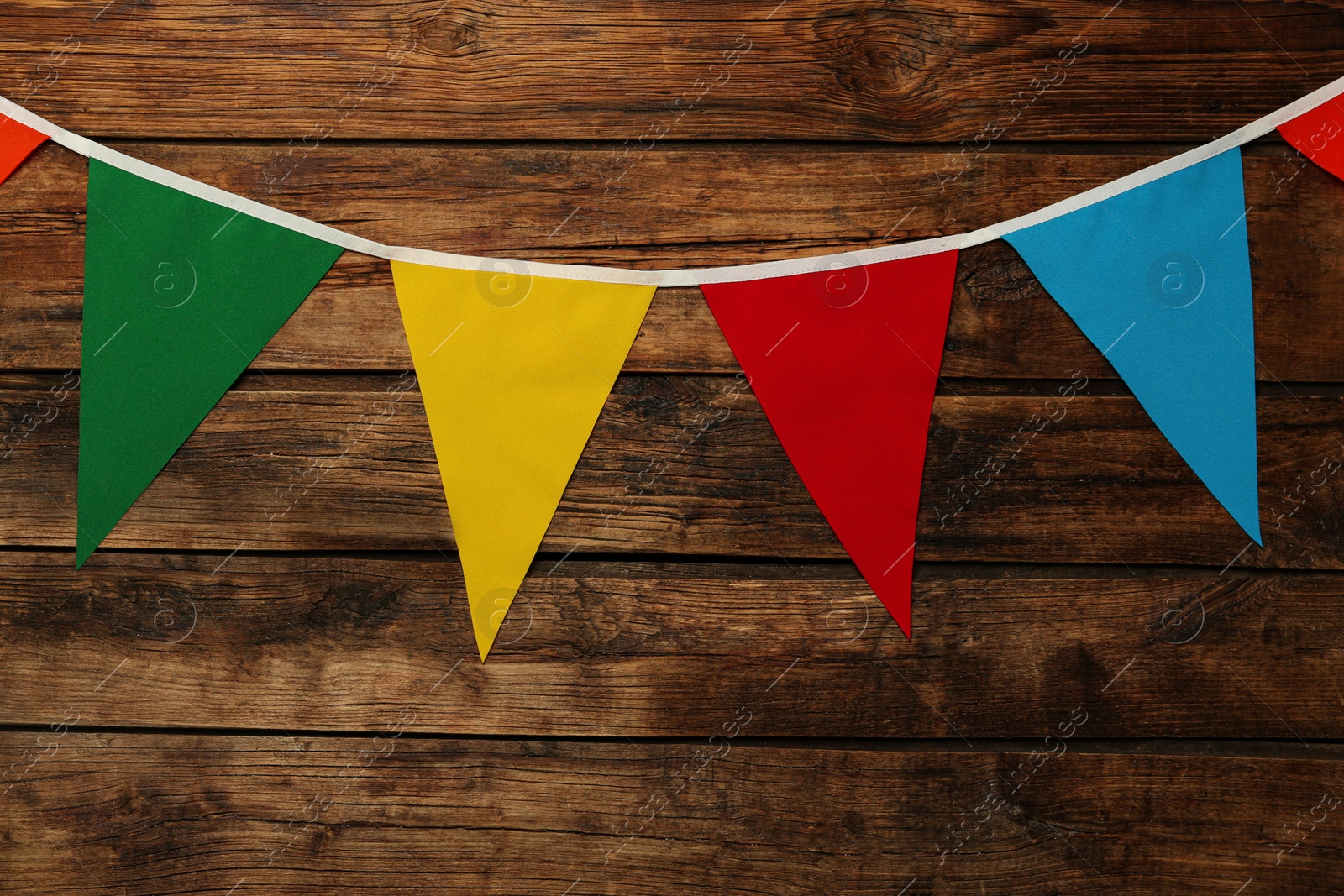 Photo of Bunting with colorful triangular flags on wooden background