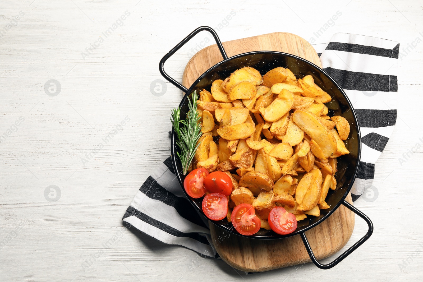 Photo of Dish of delicious oven baked potatoes with tomatoes and rosemary on white wooden background, top view. Space for text