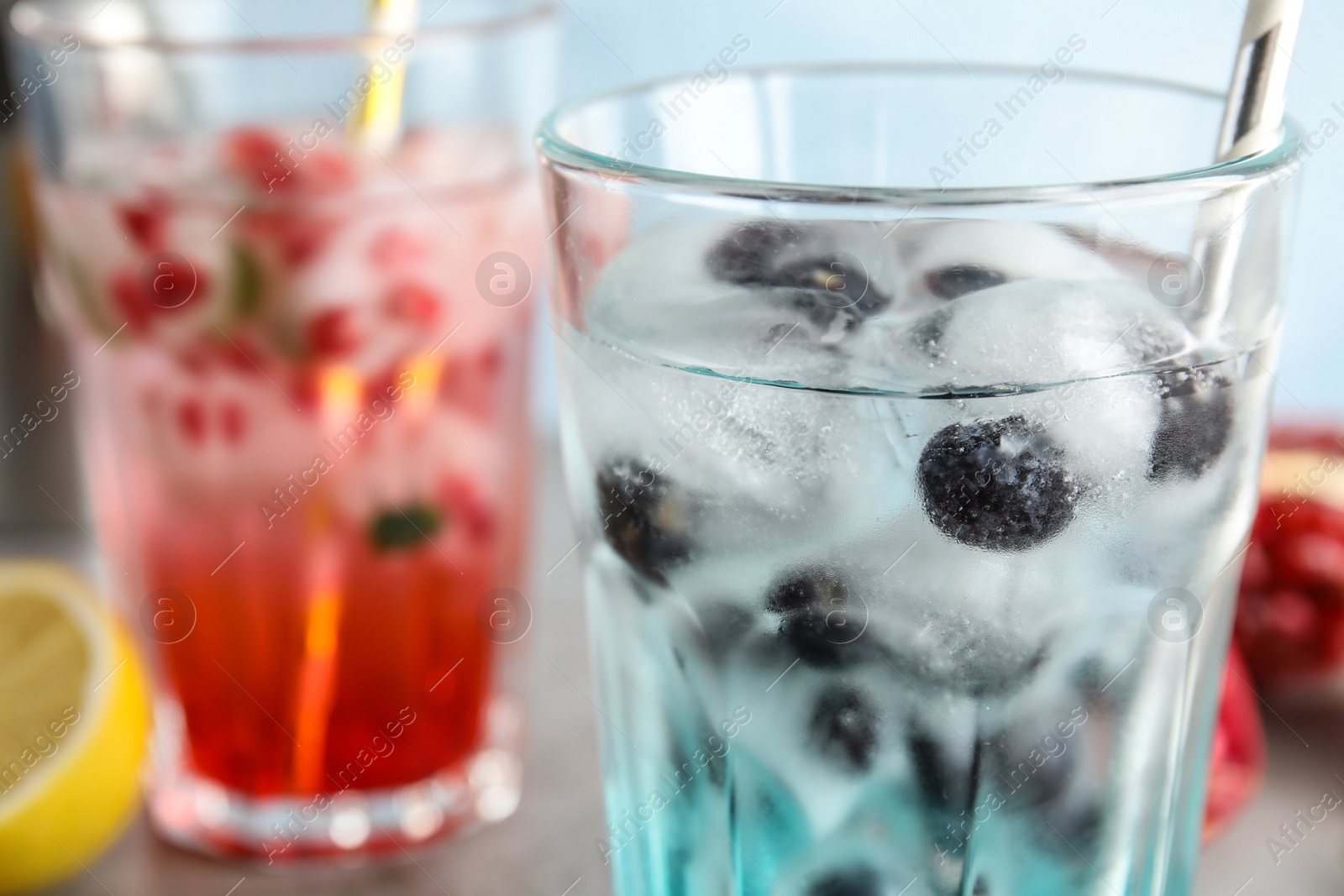 Photo of Tasty cocktail with blueberry ice cubes on table, closeup