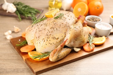 Photo of Raw chicken, orange slices and other ingredients on wooden table