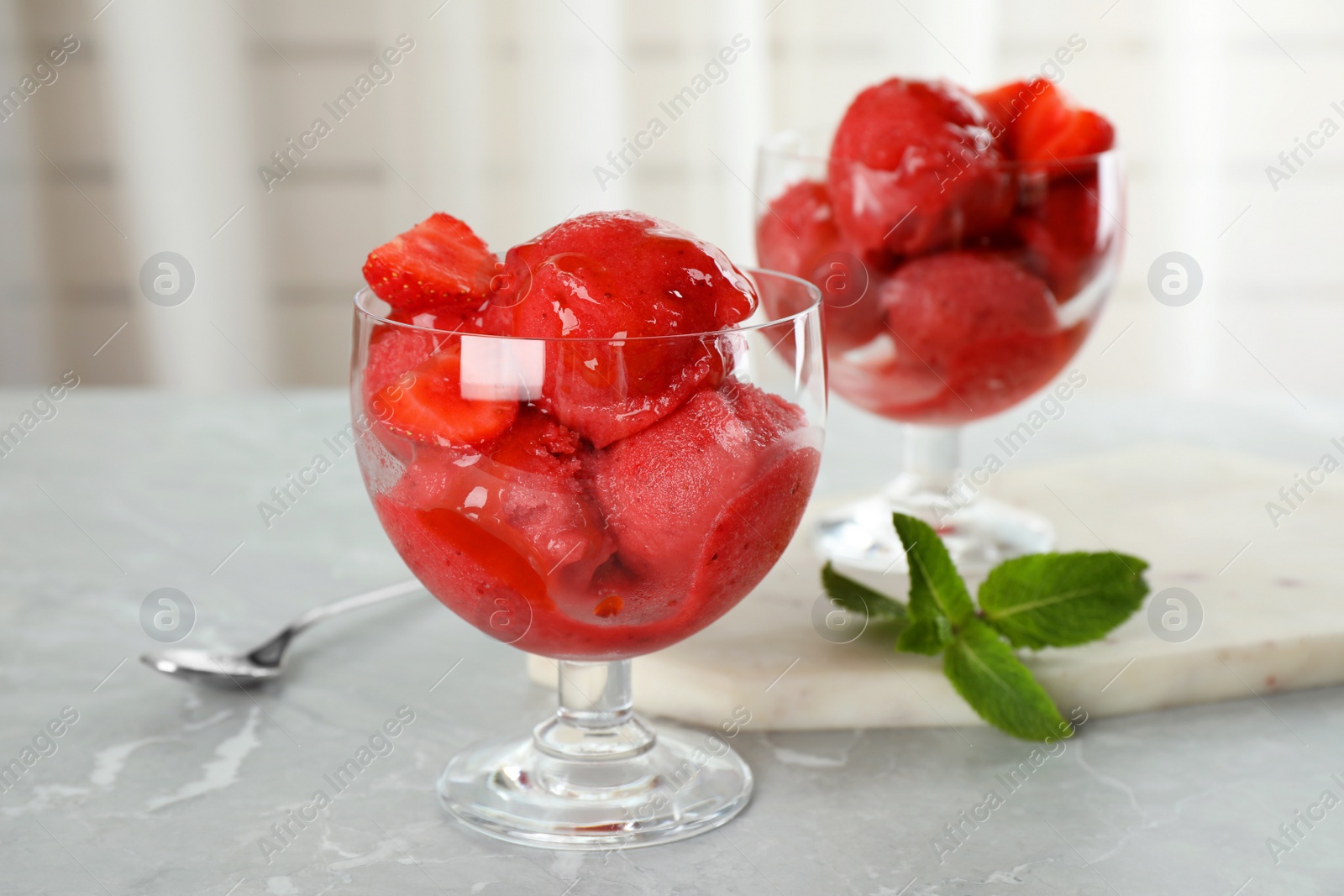 Photo of Delicious strawberry ice cream in dessert bowls on grey marble table