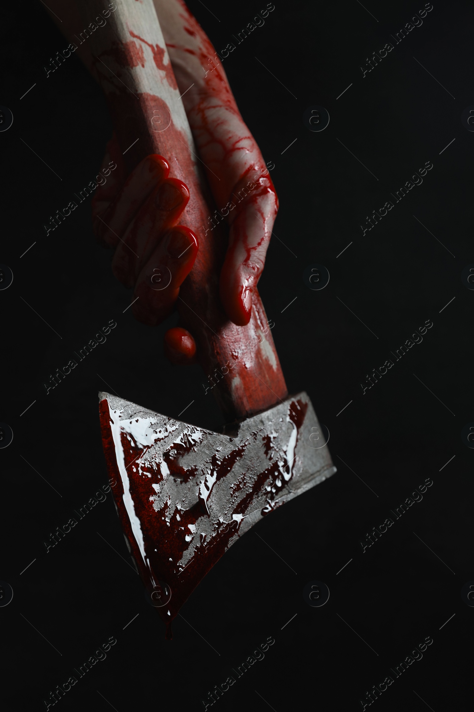 Photo of Man holding bloody axe on black background, closeup