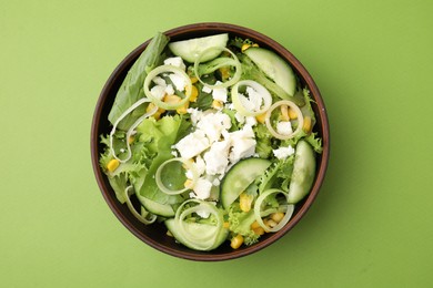 Bowl of tasty salad with leek and cheese on green table, top view