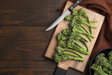 Photo of Fresh raw broccolini and knife on wooden table, flat lay with space for text. Healthy food