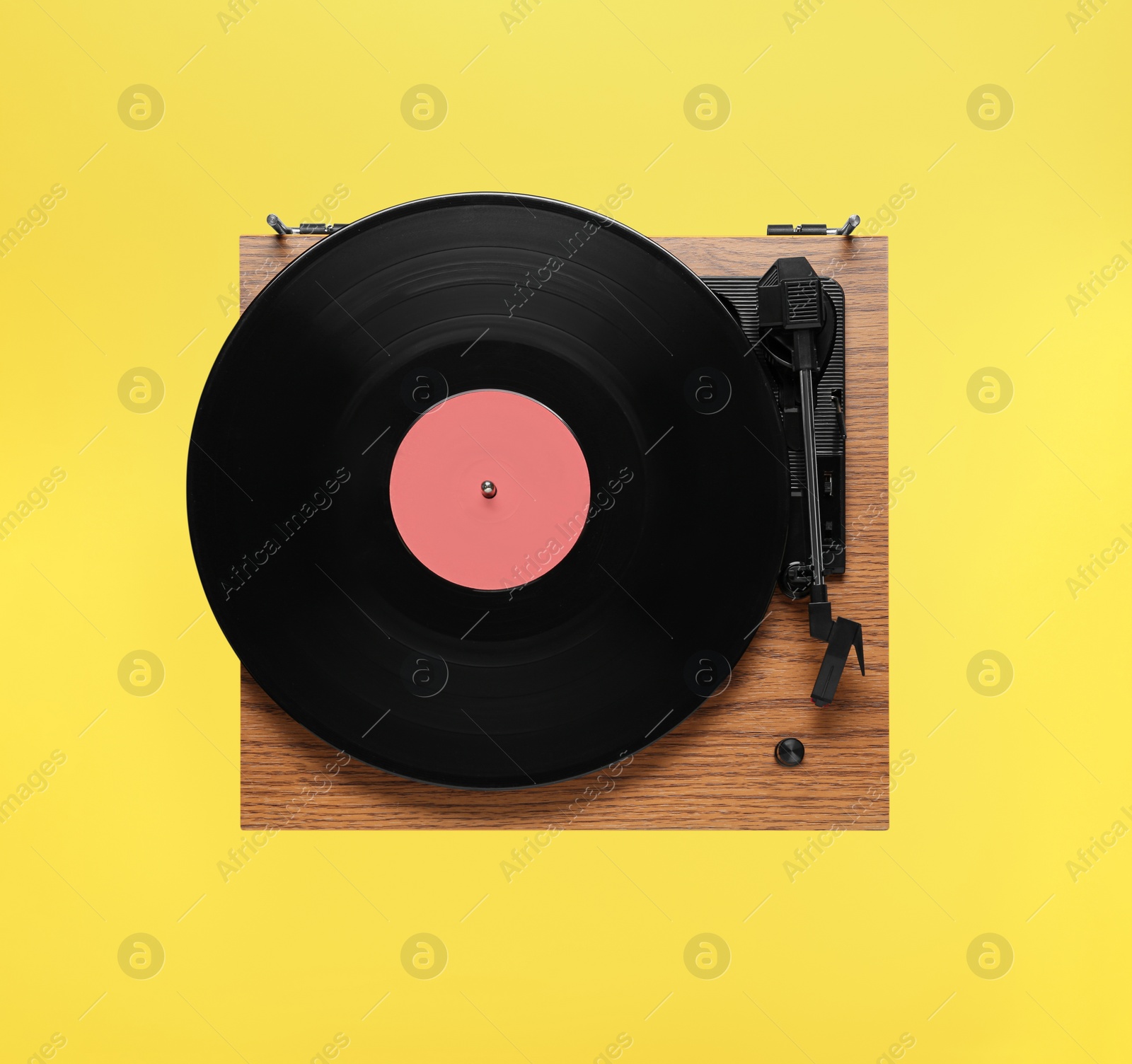 Photo of Modern turntable with vinyl record on yellow background, top view