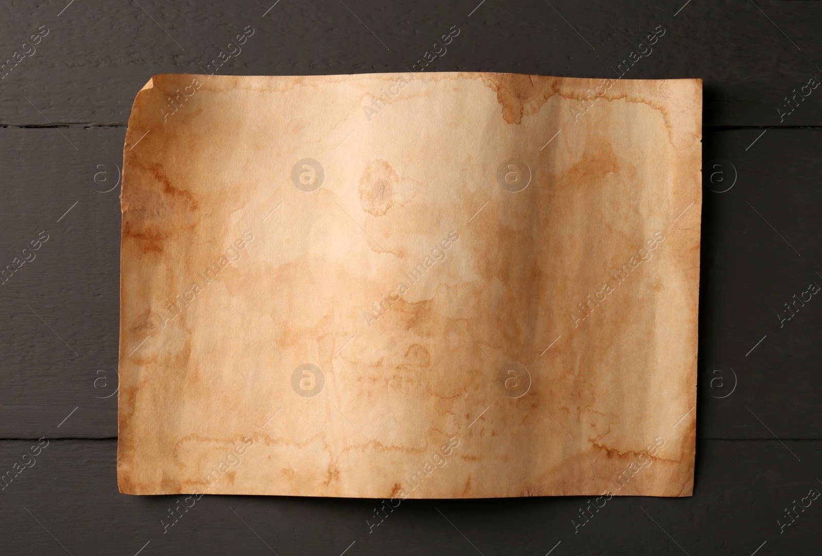 Photo of Sheet of old parchment paper on grey wooden table, top view