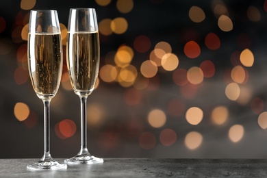 Photo of Glasses of champagne on table against blurred lights, space for text. Bokeh effect