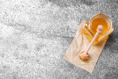 Photo of Tasty honey on grey table, flat lay. Space for text