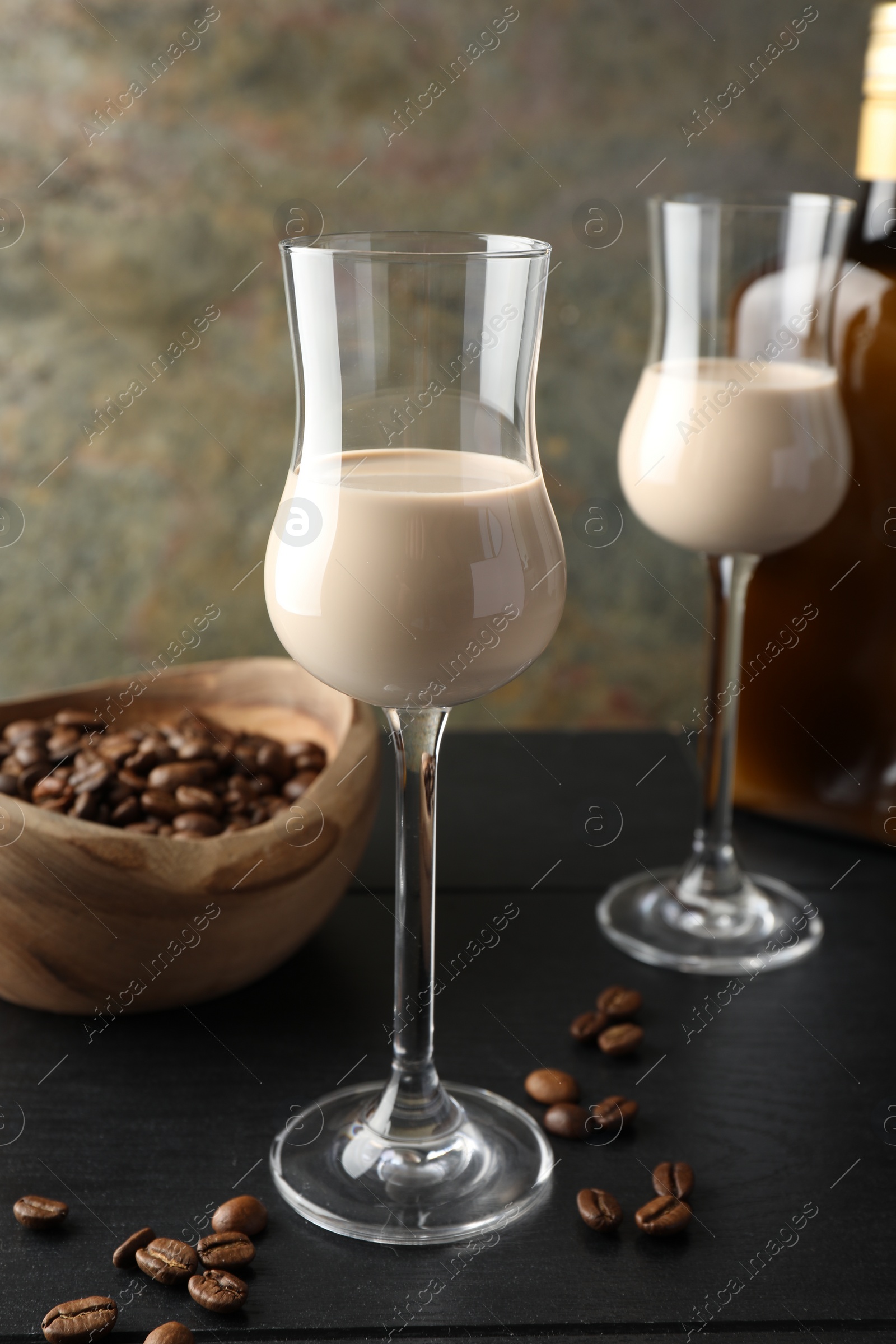 Photo of Coffee cream liqueur in glasses and beans on black wooden table