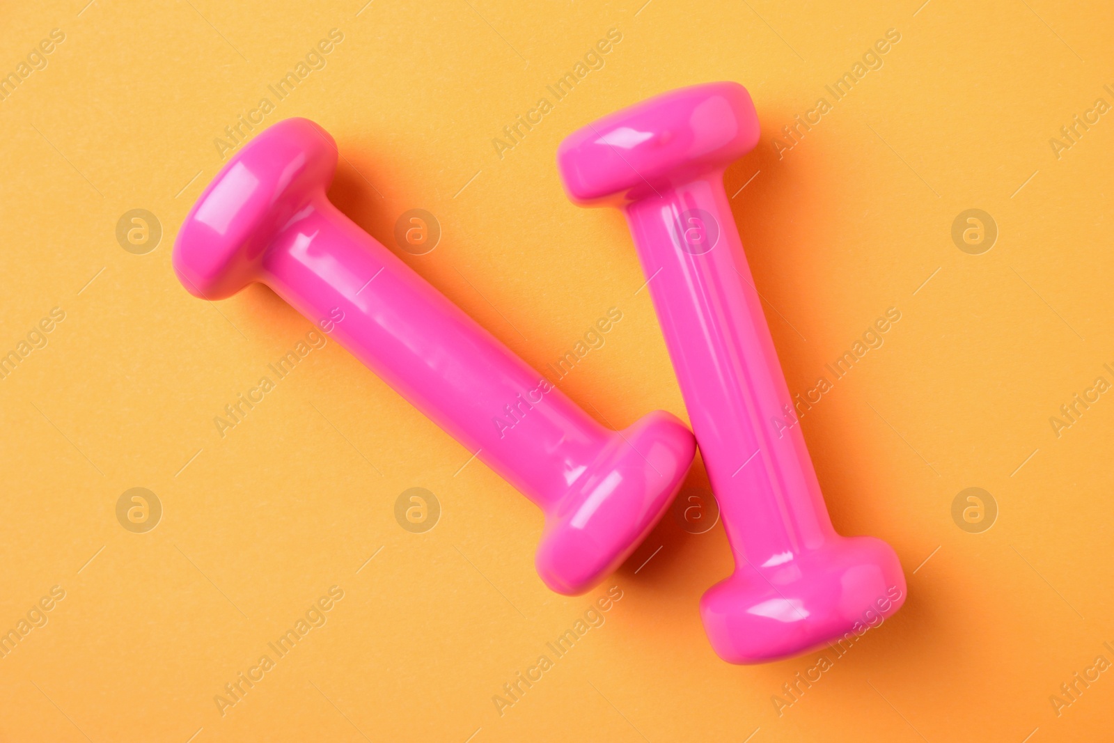 Photo of Bright dumbbells on color background, flat lay. Home fitness