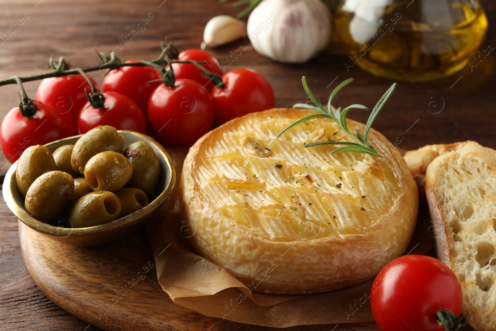 Photo of Tasty baked brie cheese served on wooden table, closeup