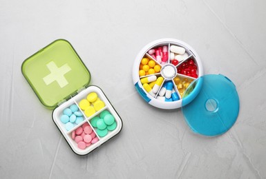 Photo of Plastic boxes with different pills on light grey stone table, flat lay