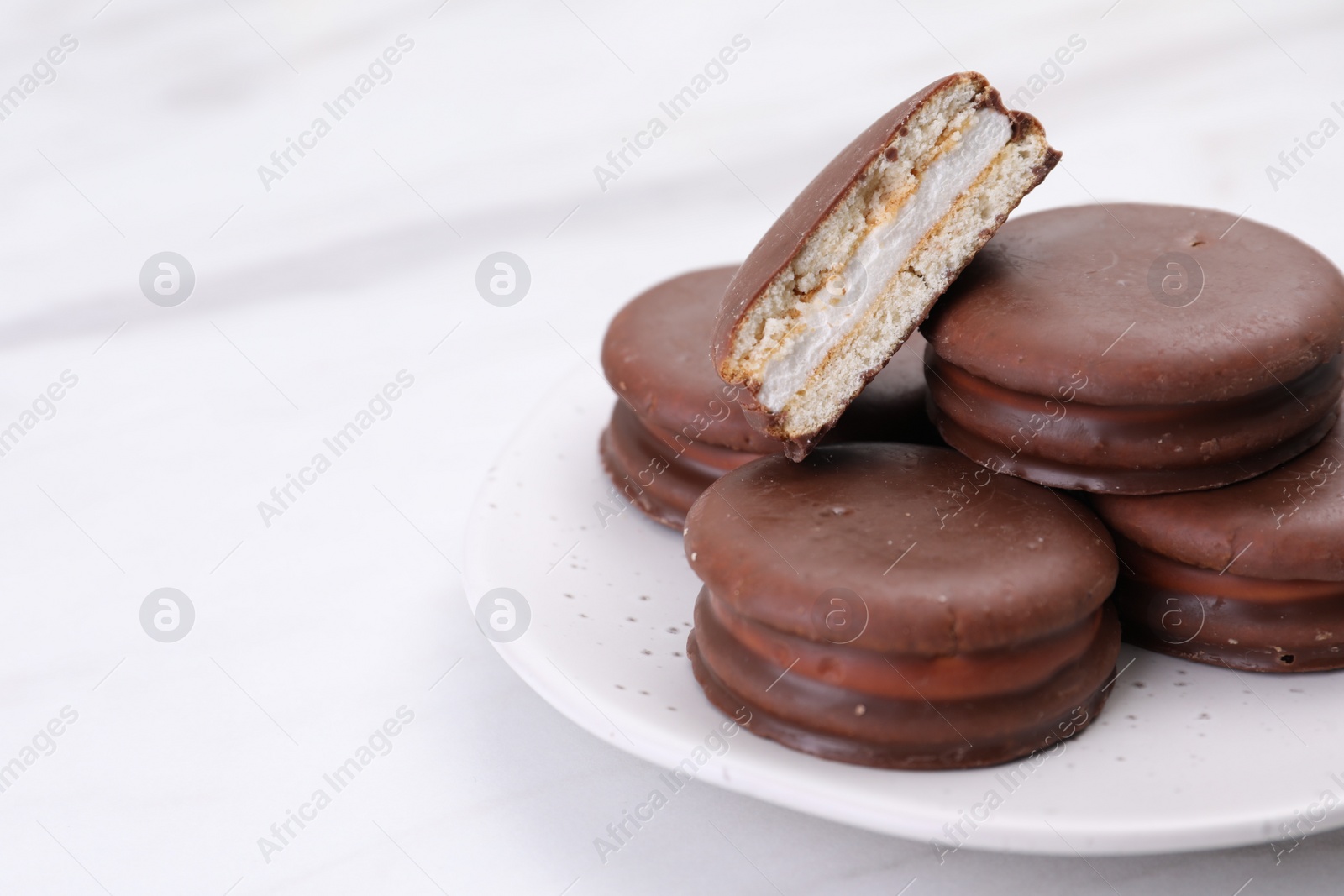 Photo of Saucer with delicious choco pies on white table, closeup. Space for text