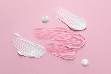 Photo of Samples of cosmetic gel and cream on pink background, top view