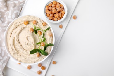 Delicious hummus with chickpeas served on white table, flat lay. Space for text