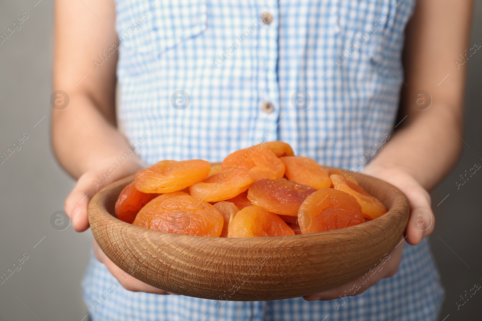 Photo of Woman holding plate with dried apricots, closeup. Healthy fruit