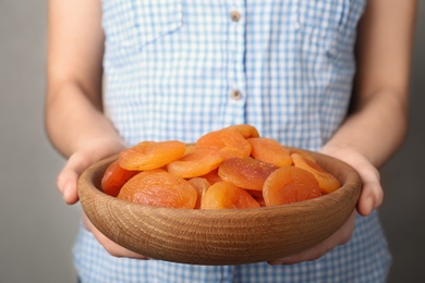 Photo of Woman holding plate with dried apricots, closeup. Healthy fruit