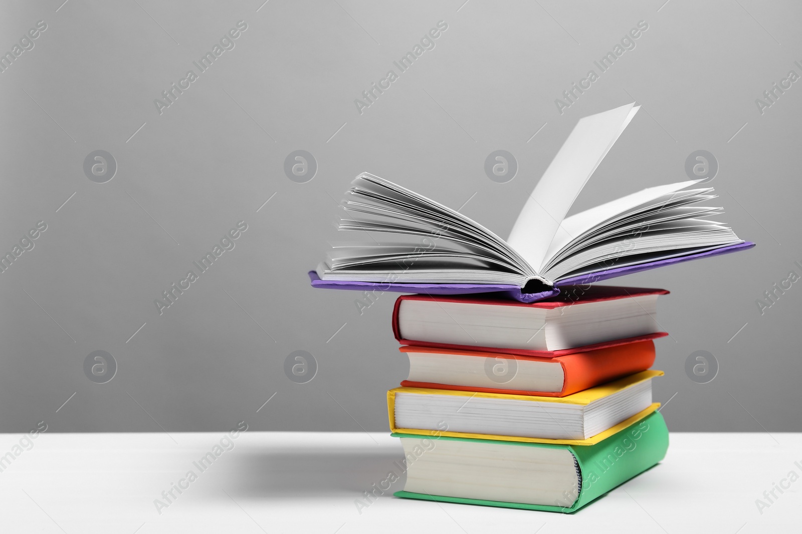 Photo of Learning foreign language. Different books on white table against gray background, space for text