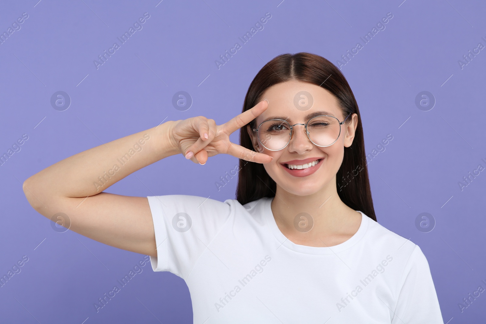 Photo of Portrait of woman in stylish eyeglasses gesturing on violet background