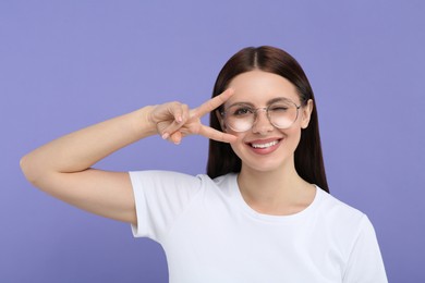 Portrait of woman in stylish eyeglasses gesturing on violet background