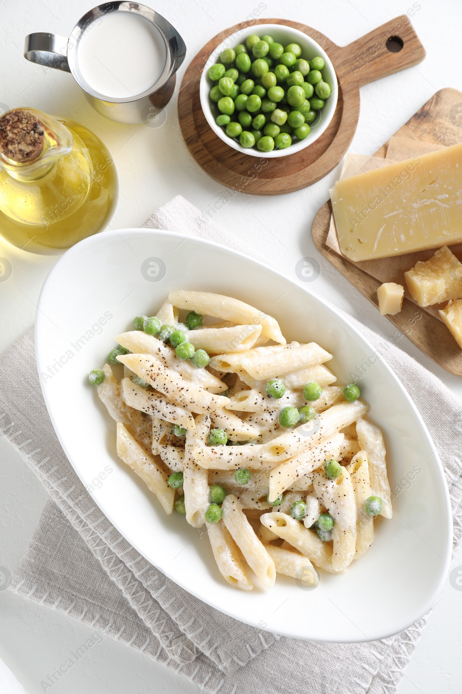 Photo of Delicious pasta with green peas and other ingredients on white table, top view