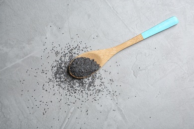 Photo of Spoon with poppy seeds on grey background, top view