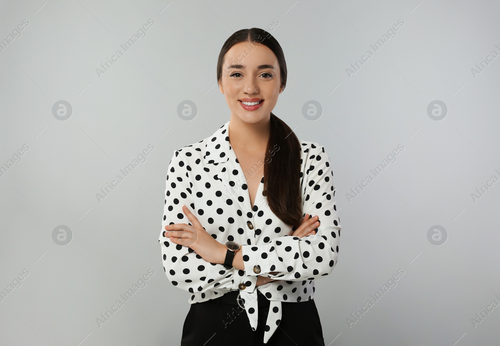 Photo of Portrait of beautiful young woman in polka dot blouse on light grey background