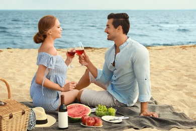 Photo of Beautiful young couple having picnic at sea beach