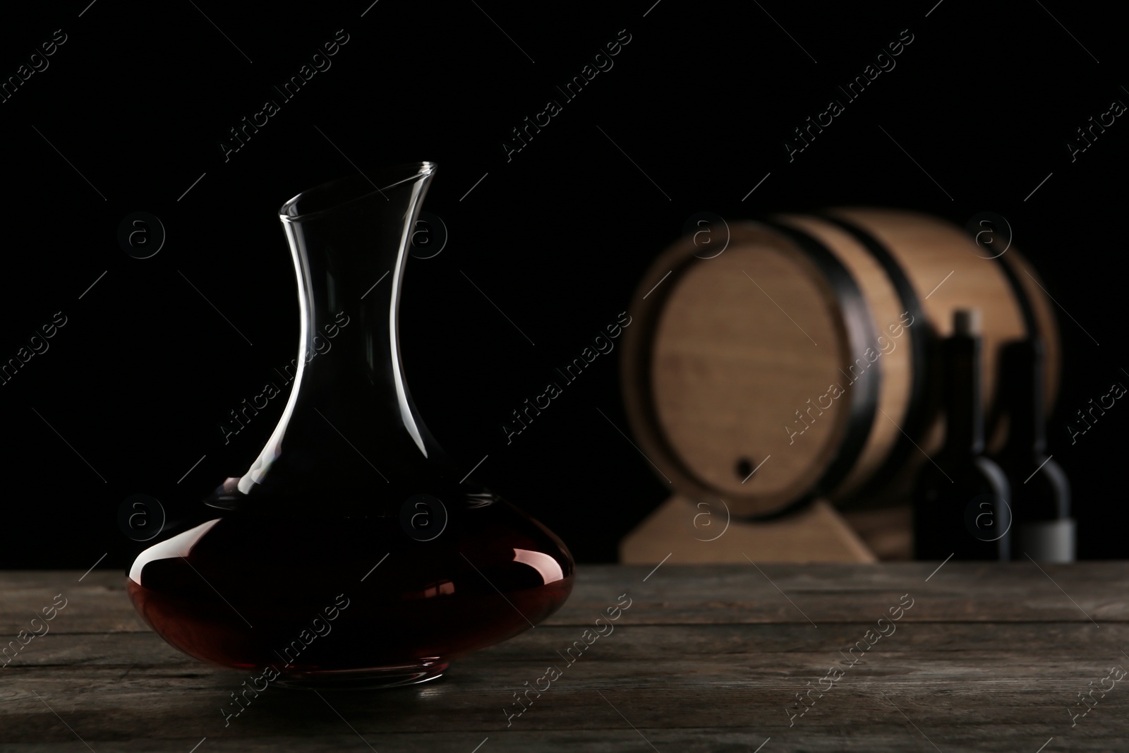 Photo of Elegant decanter with red wine on table against dark background