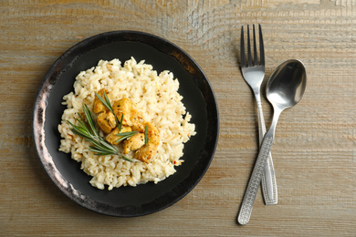 Photo of Delicious chicken risotto on wooden table, flat lay