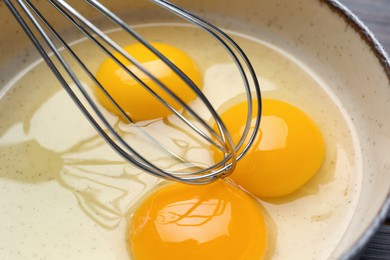 Photo of Whisking eggs in bowl on table, closeup