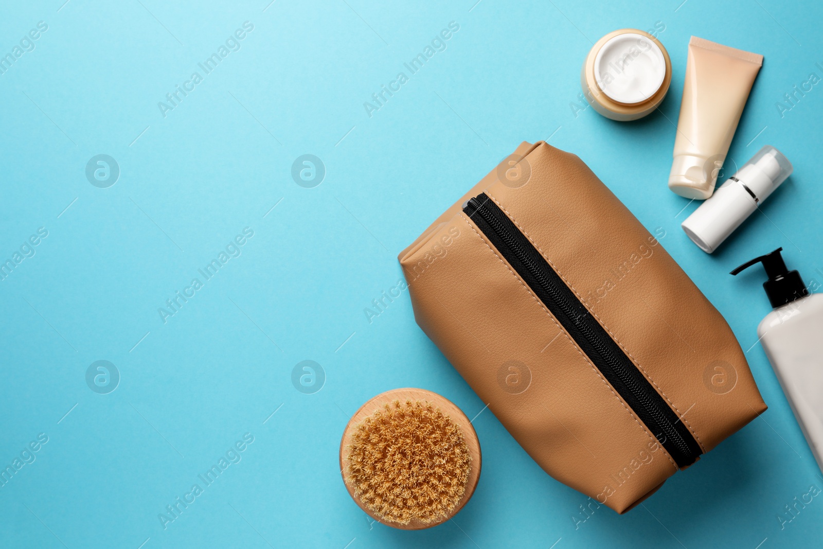 Photo of Preparation for spa. Compact toiletry bag and different cosmetic products on light blue background, flat lay. Space for text