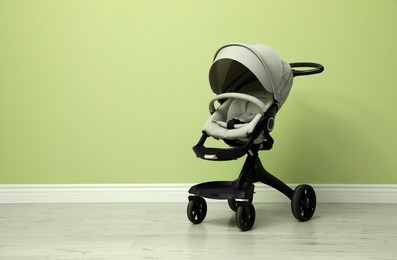 Baby carriage. Modern pram near light green wall, space for text