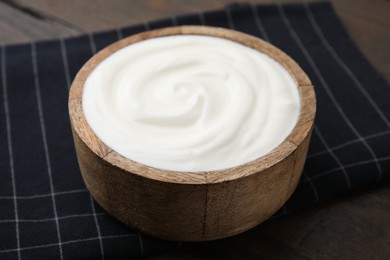 Delicious natural yogurt in bowl on wooden table, closeup