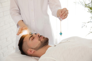 Photo of Young man during crystal healing session in therapy room