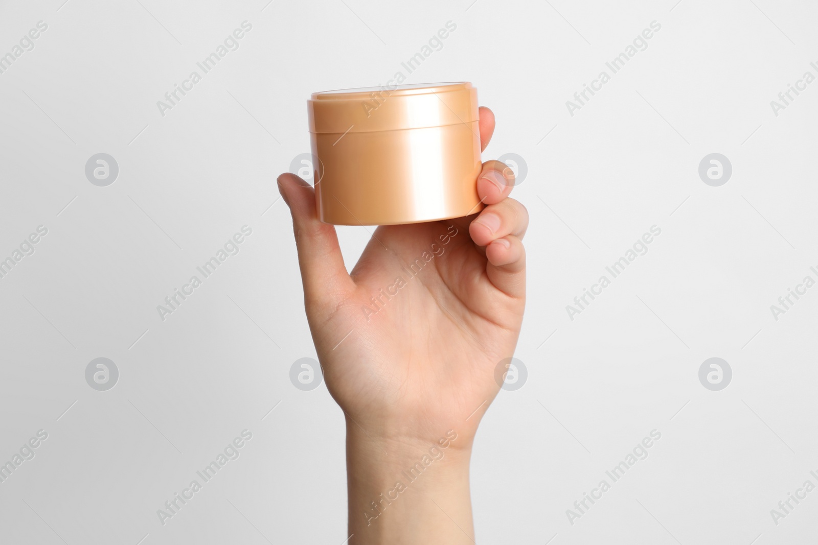 Photo of Woman holding jar of face cream on white background, closeup