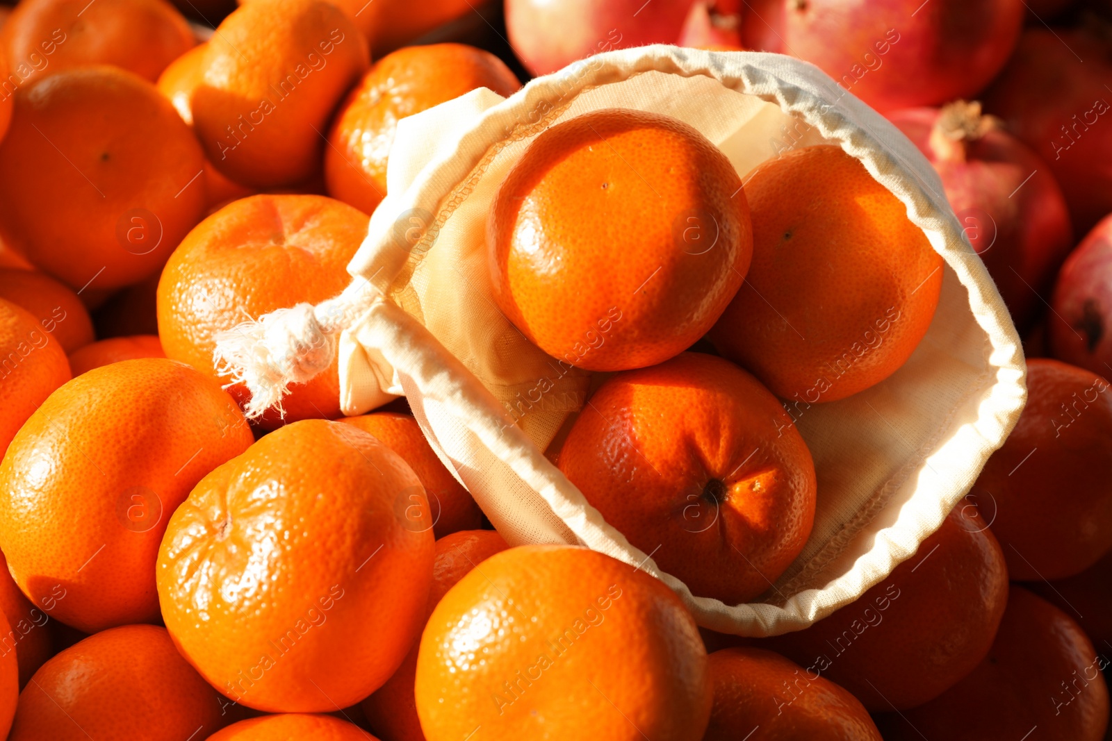 Photo of Cotton eco bag with fruits on tangerines, closeup. Life without plastic