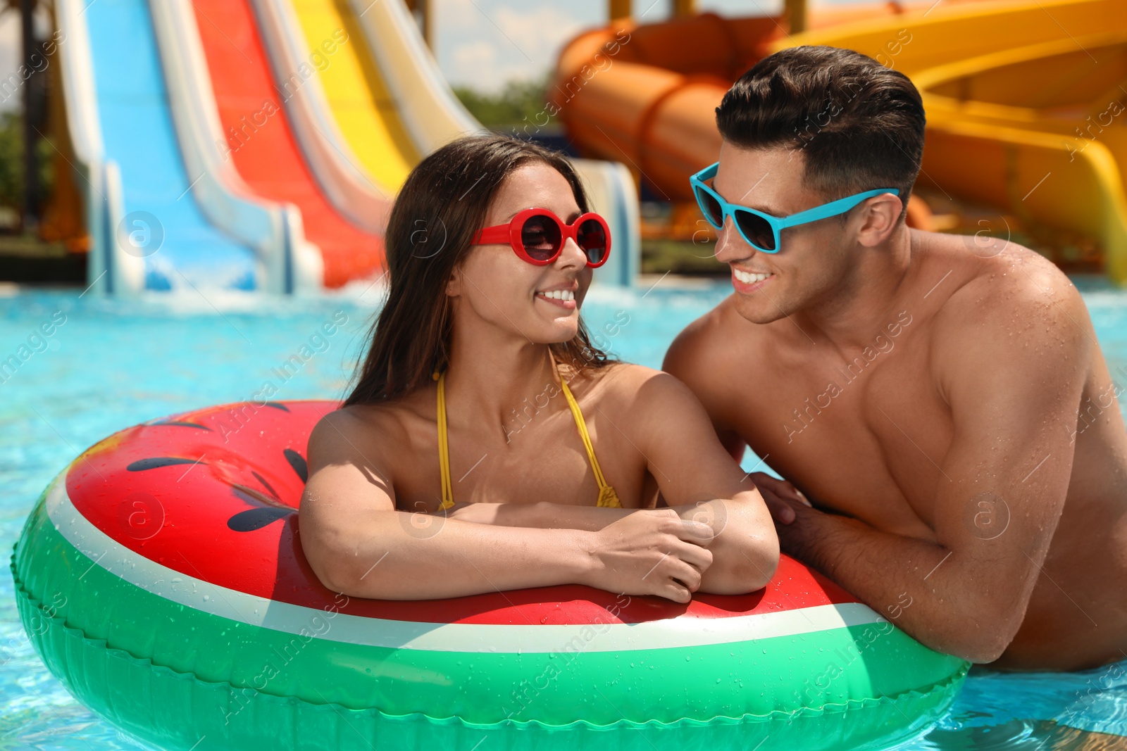 Photo of Happy couple with inflatable ring at water park. Summer vacation