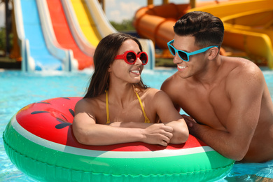 Photo of Happy couple with inflatable ring at water park. Summer vacation