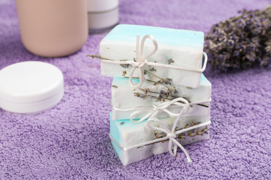 Photo of Natural handmade soap bars on lilac towel, closeup