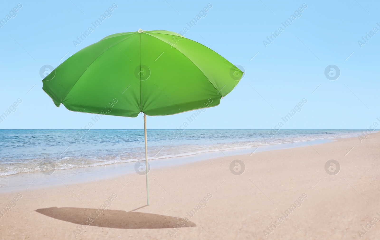 Image of Open big beach umbrella on sandy coast 