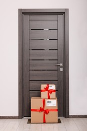 Photo of Christmas gift boxes on floor near door. Sending present by mail