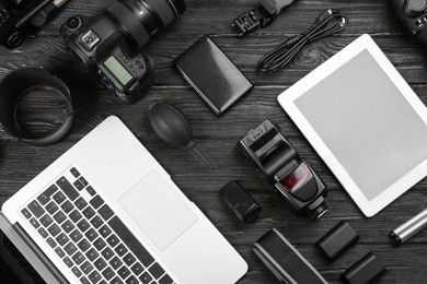 Flat lay composition with camera and video production equipment on black wooden table