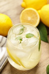 Cool freshly made lemonade in glass on wooden table, closeup