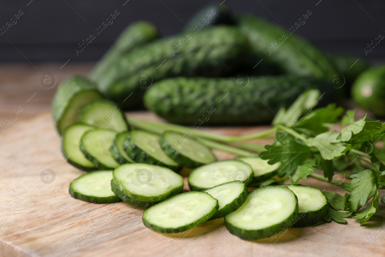 Photo of Fresh ripe cucumbers and parsley on wooden table, closeup