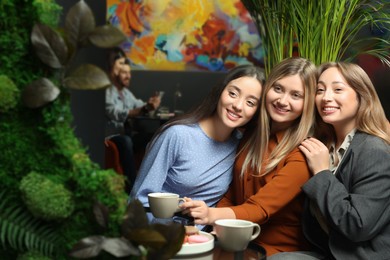 Photo of Young women flirting with guys at next table in cafe