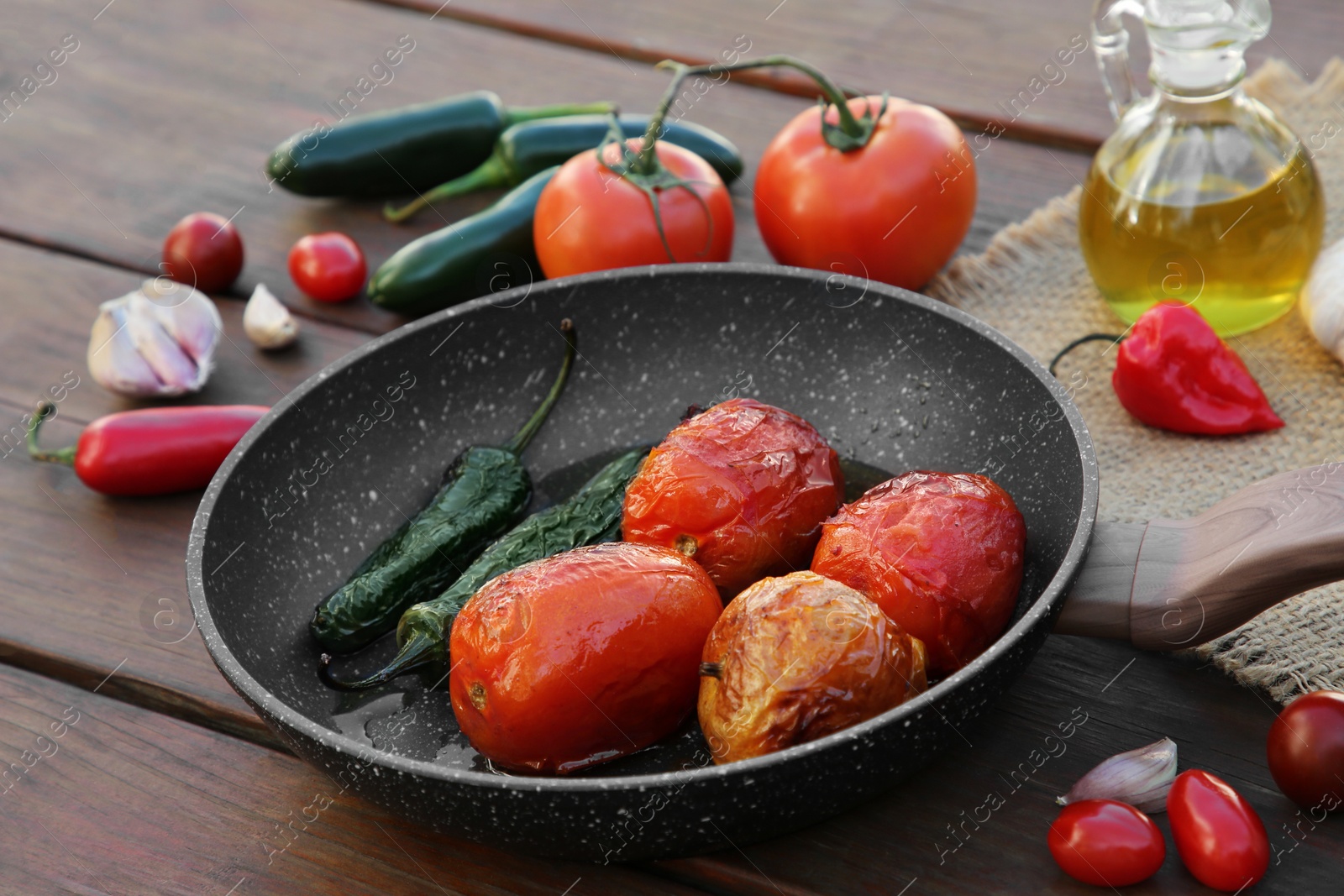 Photo of Frying pan and ingredients for salsa sauce on wooden table