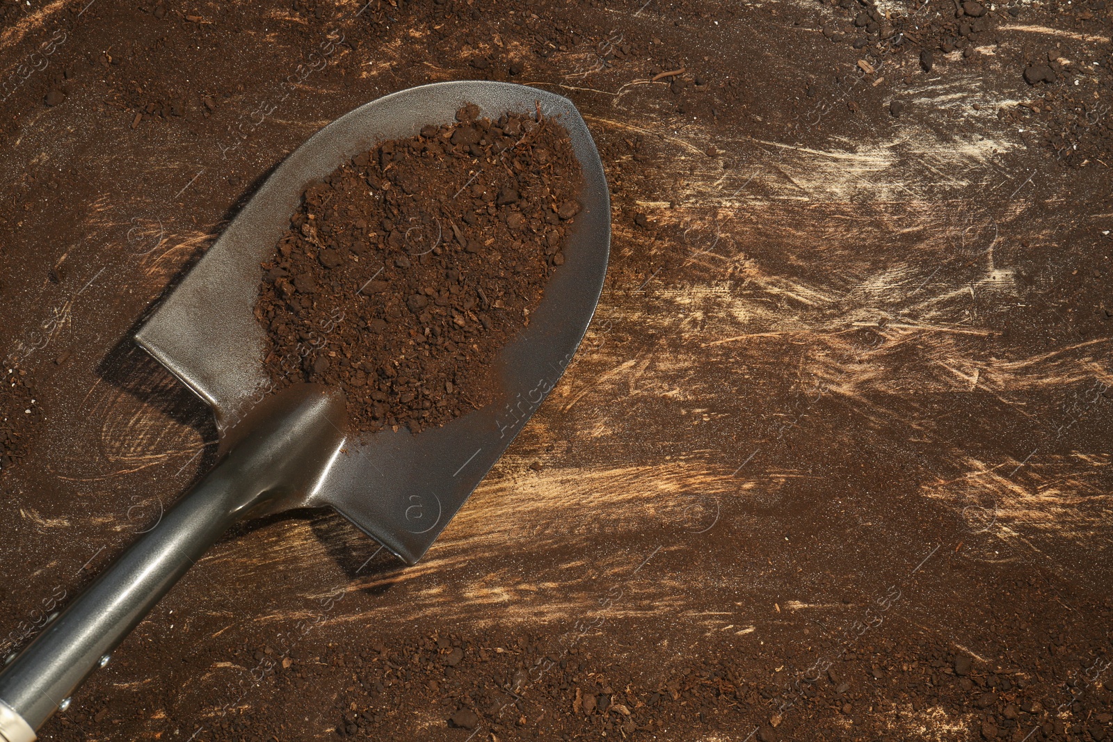 Metal shovel with fertile soil on dirty wooden surface, top view. Space for text Photo of Metal shovel with fertile soil on dirty wooden surface, top view. Space for text