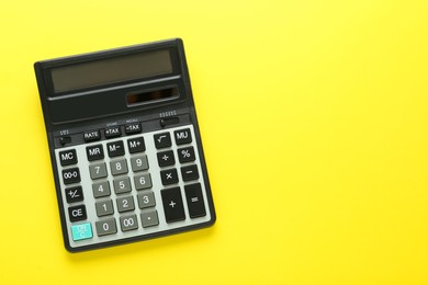 Modern calculator on yellow background, top view. Space for text